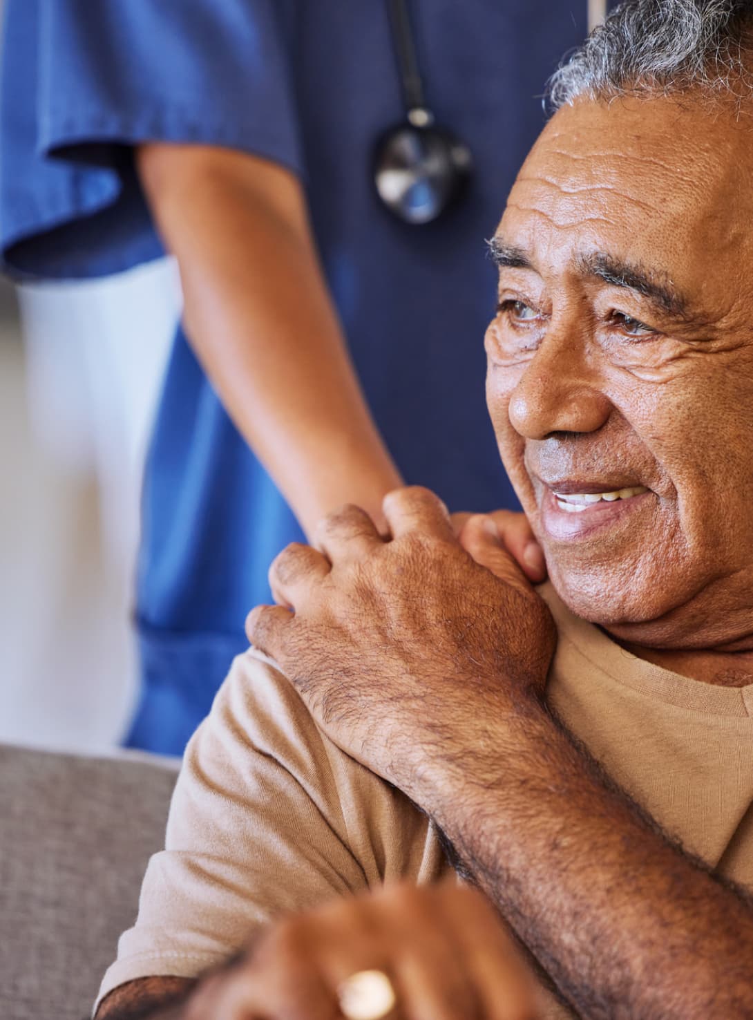 elderly man smiling with caregiver’s hand on shoulder