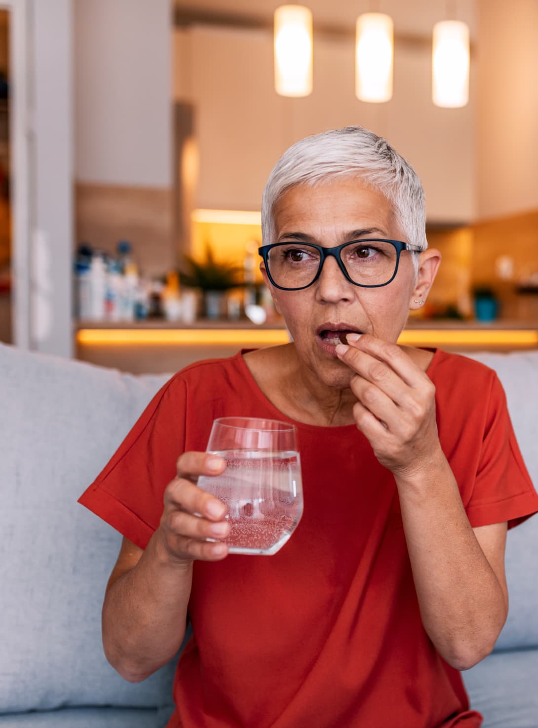woman taking medication on her couch at home as part of a medication adherence program