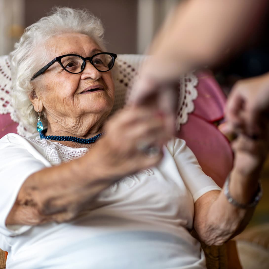 elderly-patient-being-helped-out-of-chair@2x